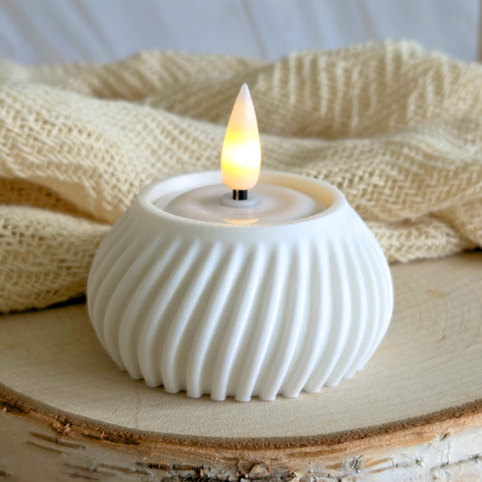 Hvid flute fyrfadsstage med tændt LED-lys – lyse, rolige toner i interiør