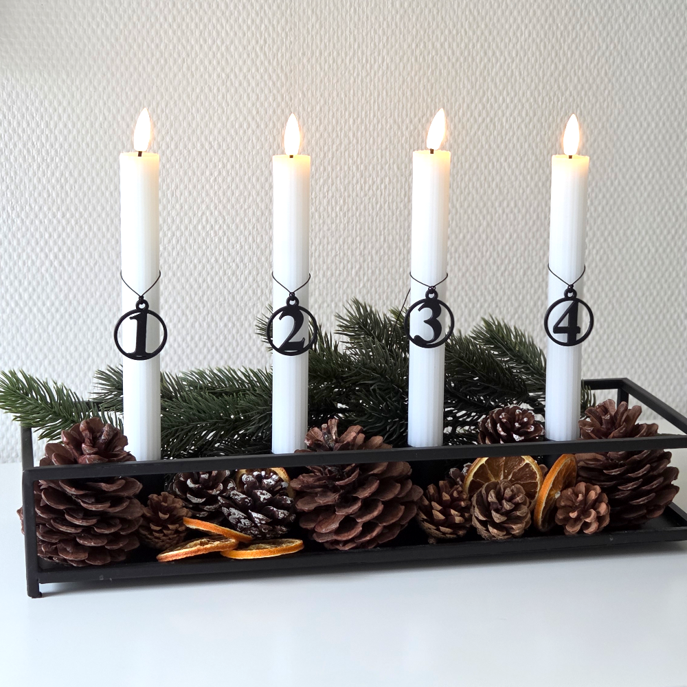 Sorte adventstal 1–4 på hvide LED kalenderlys i sort bakke med gran, kogler og tørrede appelsiner – rolig adventsstemning valgt med omtanke