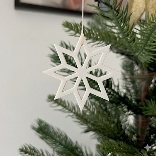 Hvid stjerneformet julepynt hængende på juletræ – elegant dekoration til grene og adventsgaver.