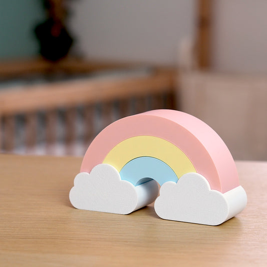 Regnbue dekoration til børneværelse i dansk design placeret ved puslebord i bløde farver