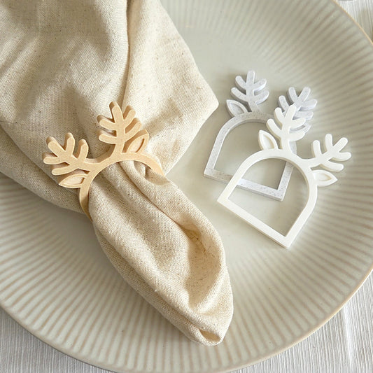 Rensdyr servietring i birk om stofserviet med en juleservietring i marmorlook og en i hvid på tallerken