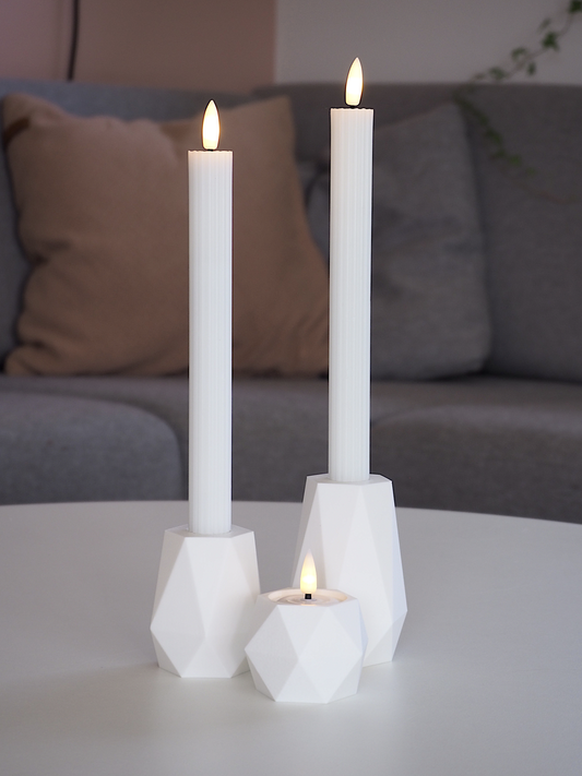 Hvid GEOMETRIC LED lysestagesæt på bord med rolige toner