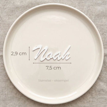 Bordkort med navn Noah i hvid, liggende på tallerken