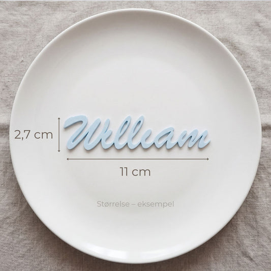 Bordkort med navn William i lyseblå, liggende på tallerken