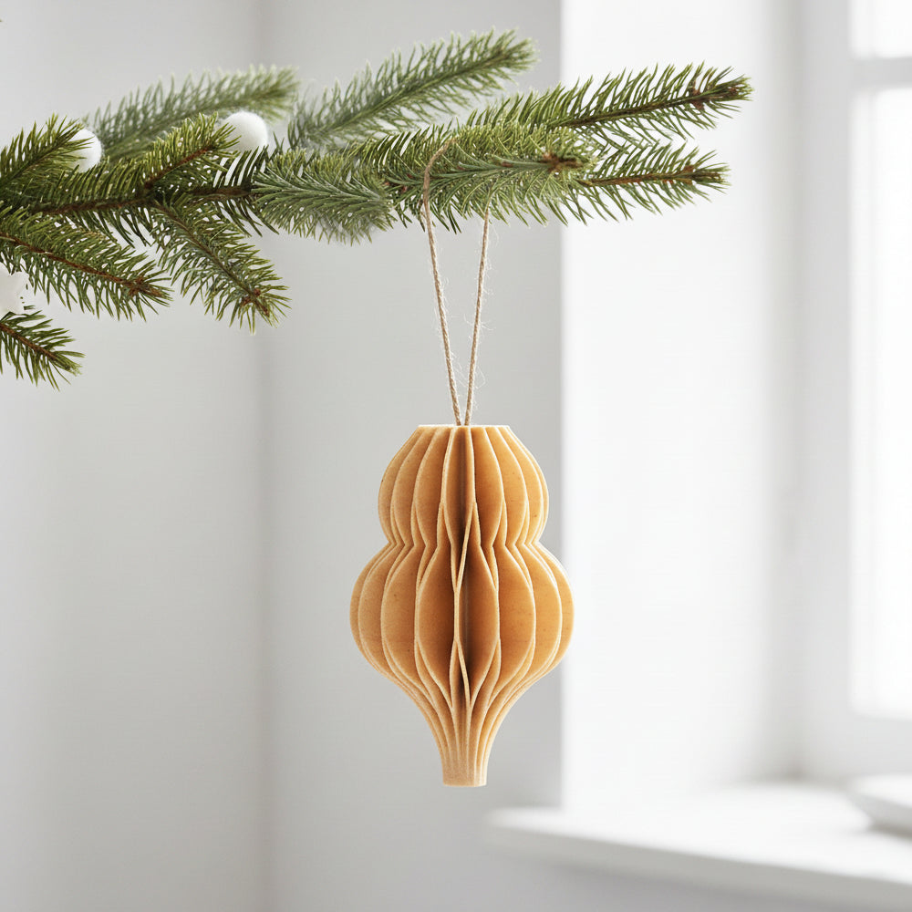 Birk farve honeycomb dråbe som julepynt på en grøn gren – enkel og varm dekoration til juletræ eller vintergrene.