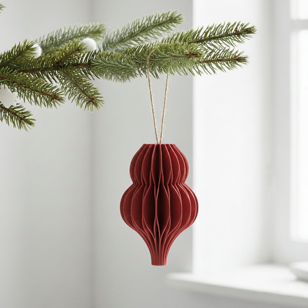 Rød honeycomb dråbe som julepynt på en grøn gren – enkel og varm dekoration til juletræ eller vintergrene.