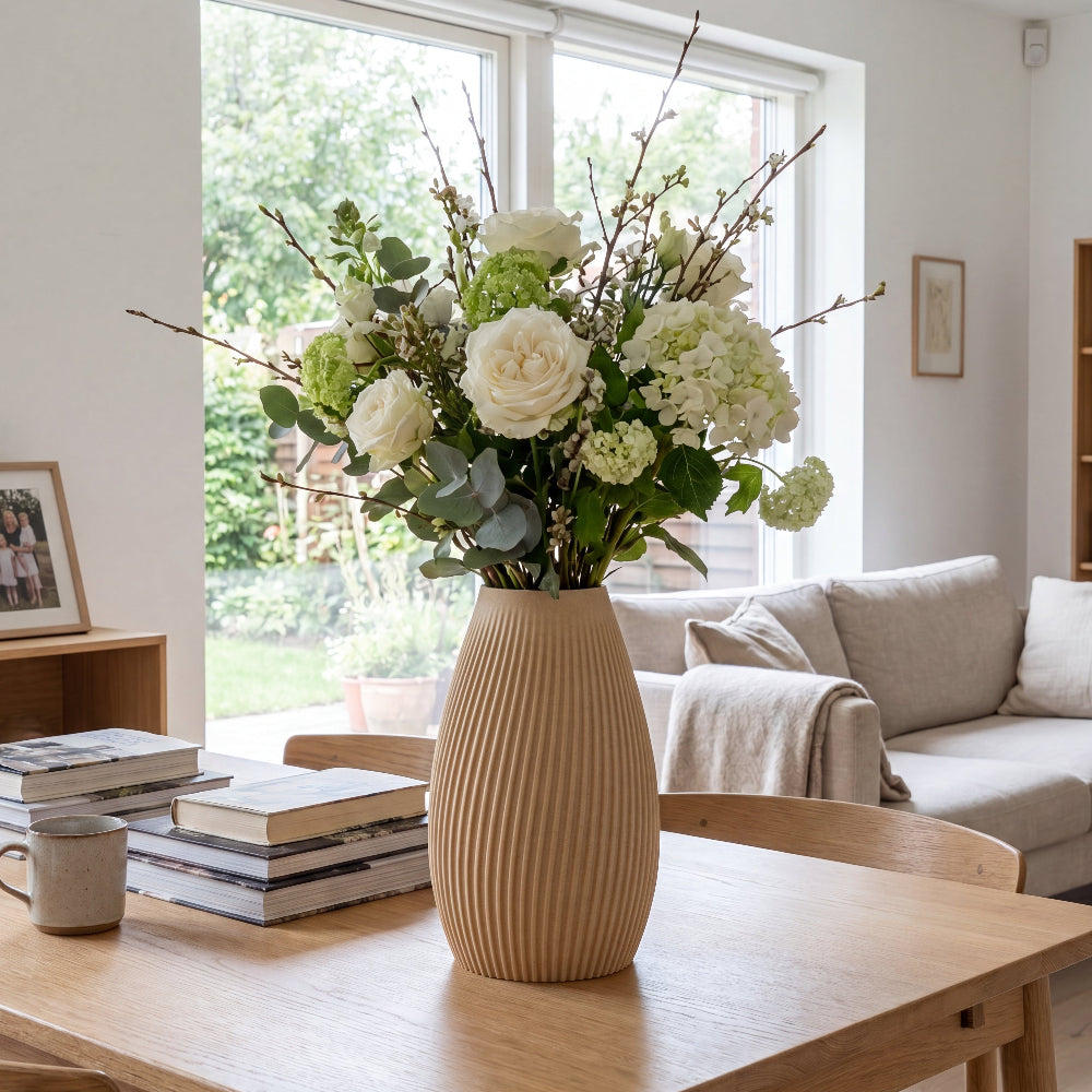 Flute vase i birk fra Hartli med friske blomster på spisebord i et lyst hjem.