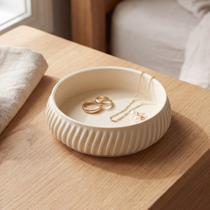 FLUTE smykkeskål i cream med ringe og halskæde på lyst egetræsbord