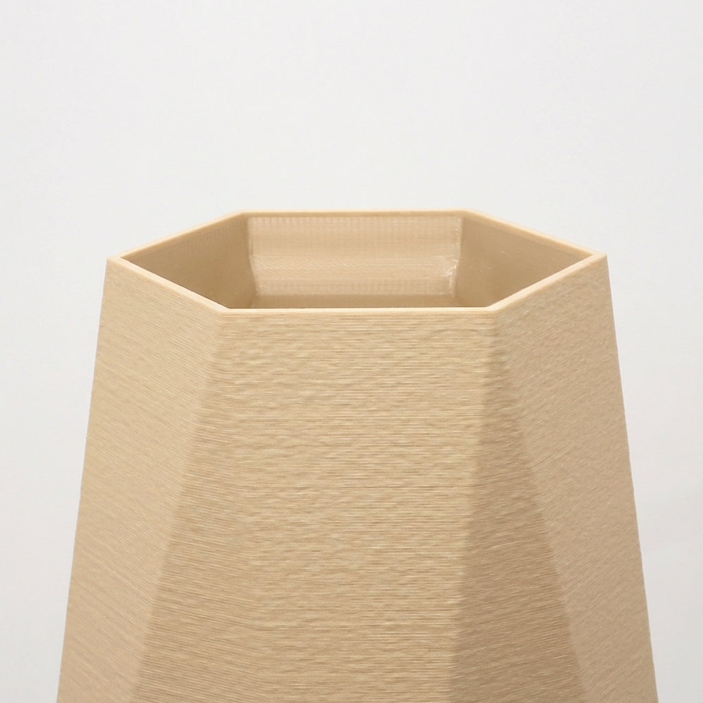 Detalje af beige geometrisk vase med markante kanter og mat overflade