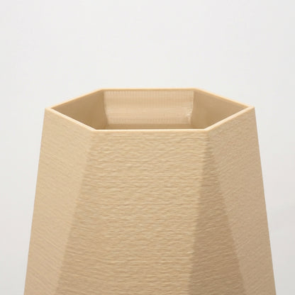 Detalje af beige geometrisk vase med markante kanter og mat overflade