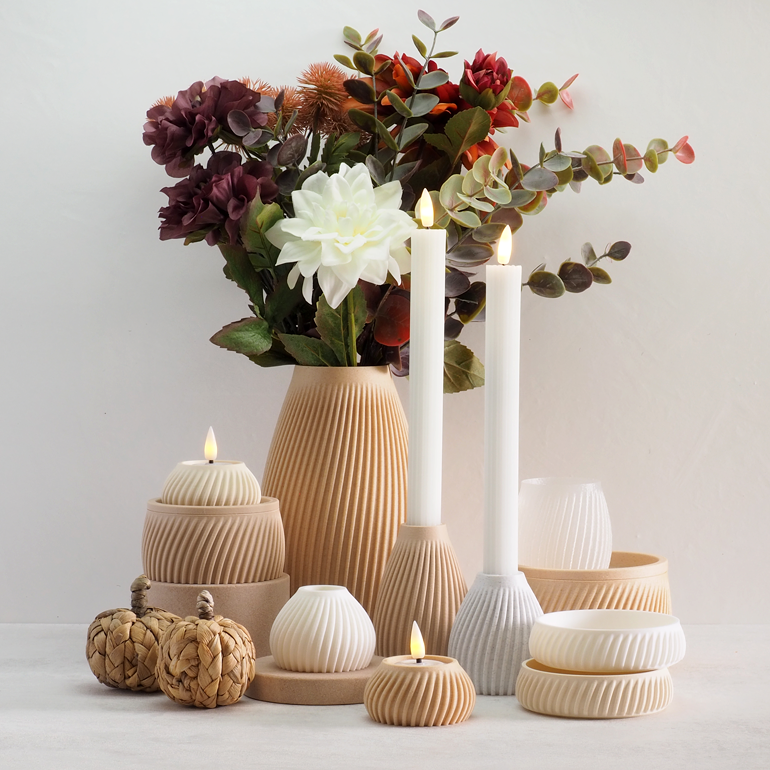 FLUTE kollektion fra Hartli med 3D-printede vaser, lysestager og fyrfadsstager i bæredygtige materialer, vist i varme nuancer med LED-lys og kunstige blomster i naturlig indretning