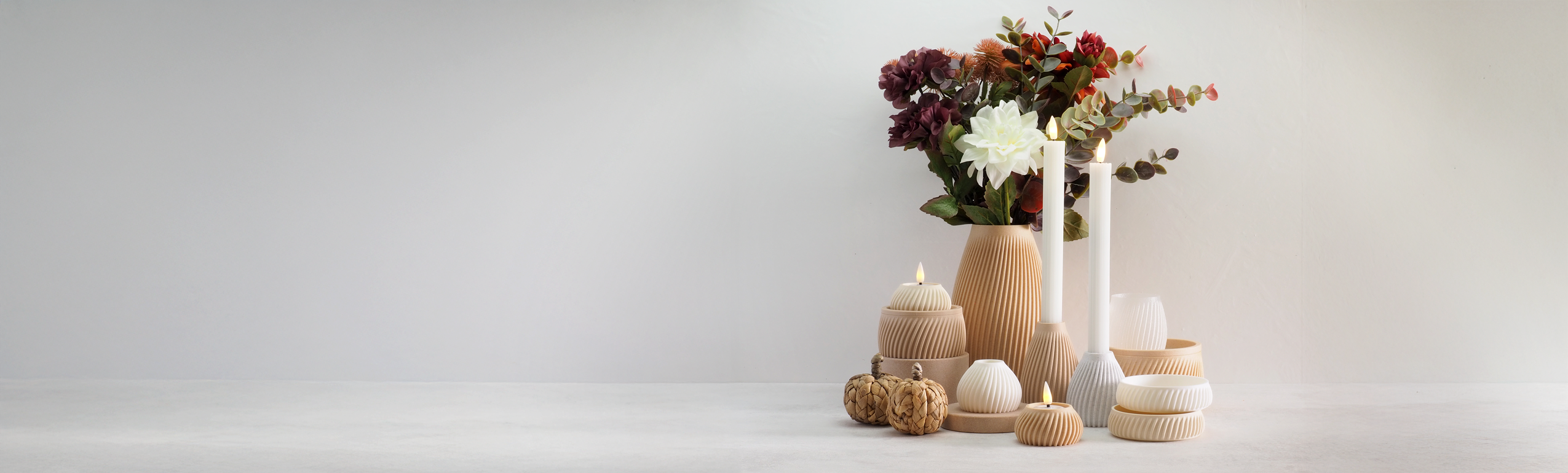 FLUTE kollektion fra Hartli med 3D-printede vaser, lysestager og fyrfadsstager i bæredygtige materialer, vist i varme nuancer med LED-lys og kunstige blomster i naturlig indretning