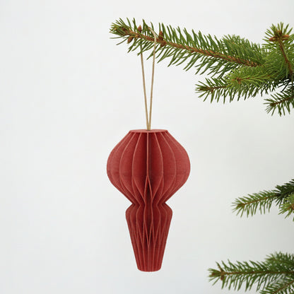 Rød honeycomb julepynt på en grøn gren – enkel og varm dekoration til juletræ eller vintergrene.