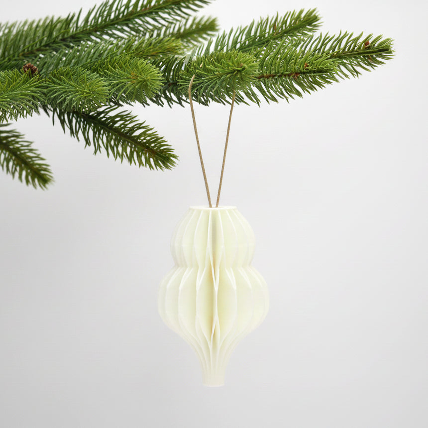 Hvid honeycomb dråbe som julepynt på en grøn gren – enkel og varm dekoration til juletræ eller vintergrene.