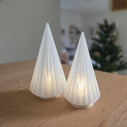 To kegle juletræ fyrfadsstager som julepynt og julelysestage på bord i roligt decemberudtryk