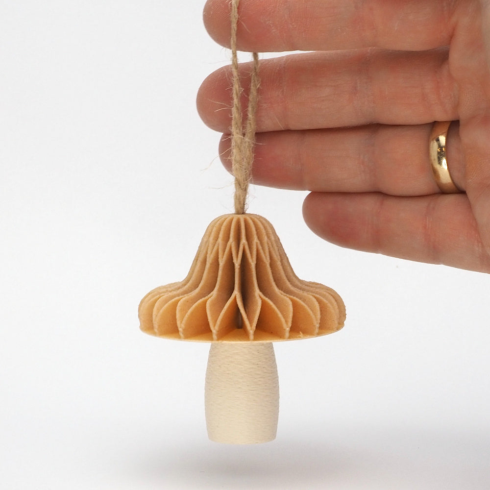 Enkeltstående mini 3D-printet svamp balancerende på en finger mod en hvid baggrund for at vise svampens lille størrelse og fine detaljer. Designet og produceret af Hartli.