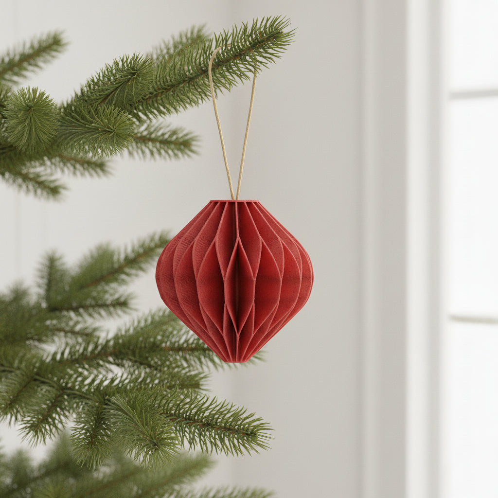 Rød honeycomb kugle som julepynt hængende på en gren – tidløs juledekoration til juletræ eller gren.