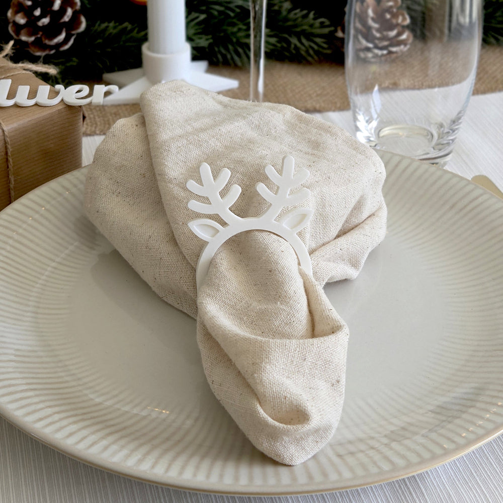 Hvid rensdyr servietring brugt som juleservietring på dækket tallerken med stofserviet