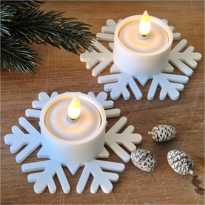 Fyrfadsstage formet som snefnug med LED-fyrfadslys, vist ovenfra på træbord med juledekoration