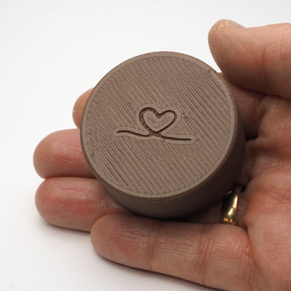 Bagsiden af lille tandfe æske til mælketænder, vist i en hånd for at illustrere størrelse