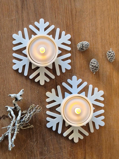 To hvide snefnug fyrfadsstager med LED fyrfadslys på træbord med naturpynt